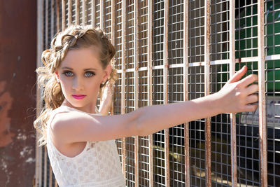 Close-up portrait of young woman standing against brick wall