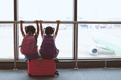 Rear view of siblings sitting at airport