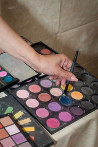 Close-up of woman hand holding make-up brush over palette
