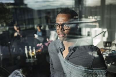 Thoughtful businessman seen through glass window