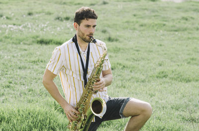 Young man with arms raised on grass