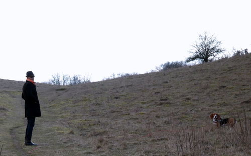 Rear view of man standing on field against clear sky