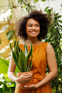 Portrait of smiling young woman standing against plants