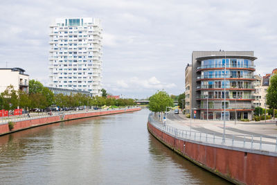 Buildings by river against sky in city