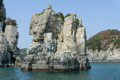 Scenic view of rock formation in sea against clear sky