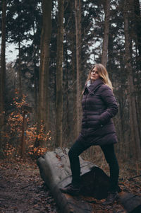 Woman standing on log in forest