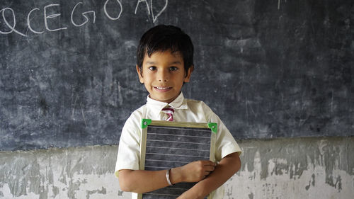 Young woman using mobile phone against wall