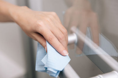 Cleaning glass door handles with an antiseptic wet wipe. 