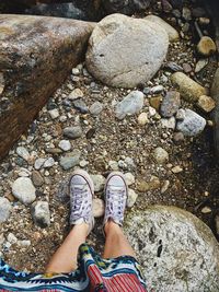 Low section of person standing on pebbles at beach