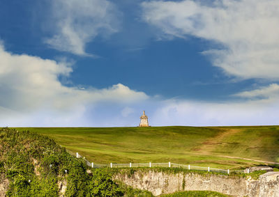 Lighthouse on field against sky