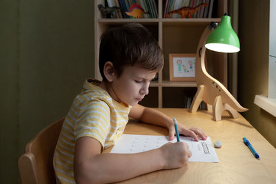 Boy drawing on book at home