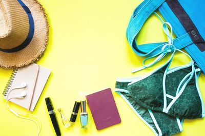 Close-up of bikini with purse and hat on yellow background