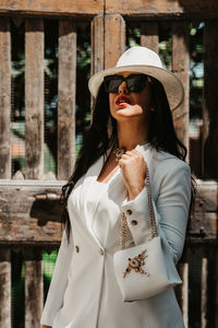 Portrait of young woman wearing hat standing by railing