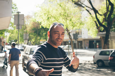 Portrait of mature man hand gesturing on sidewalk