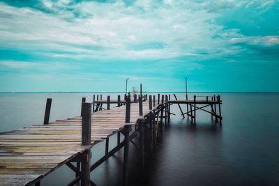 Pier on sea against cloudy sky