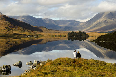 Rear view of man looking at lake against mountain range