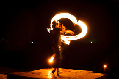 Silhouette man standing against illuminated fire at night