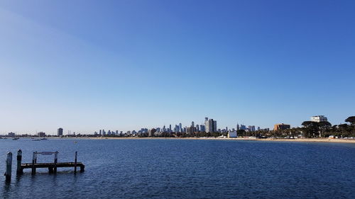 Sea by buildings against clear blue sky