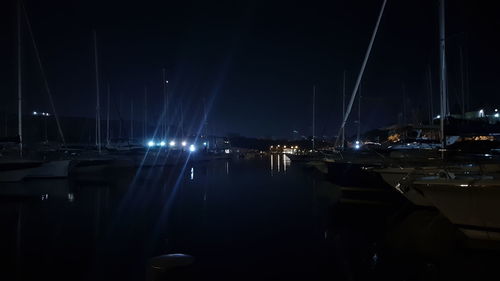 Boats moored at harbor against sky at night