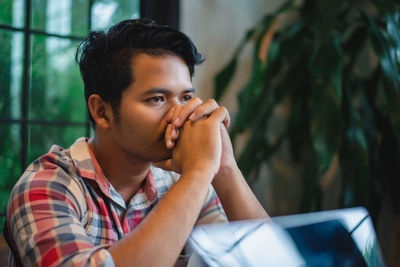 Young man sitting with hands clasped at home