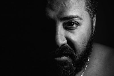 Close-up portrait of young man against black background