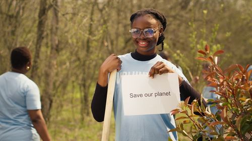 Portrait of young woman standing against plants