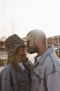 Girlfriend and boyfriend in the fence looking each other and touching noses. happy couple.