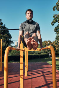 Young man doing l-sit on parallel bars during his workout in a modern calisthenics workout park