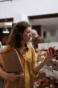 Young woman using mobile phone while sitting on table