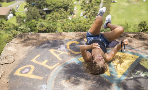 High angle view of happy woman lying on cliff with graffiti