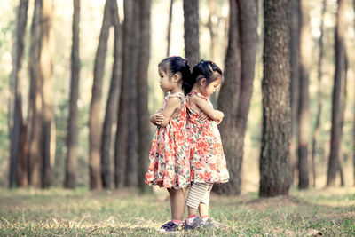 Side view full length of siblings standing on field