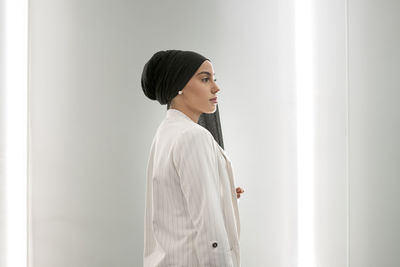 Contemplating arab woman standing by wall in shopping mall
