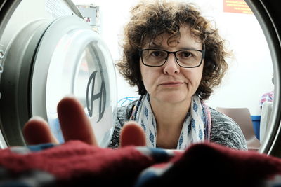 Portrait of mature woman removing laundry from washing machine