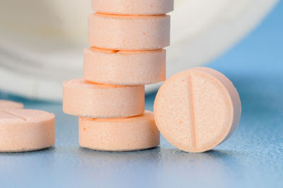 Pink tablet of medicine against light blue background, studio shot