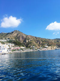 Scenic view of sea and mountains against blue sky