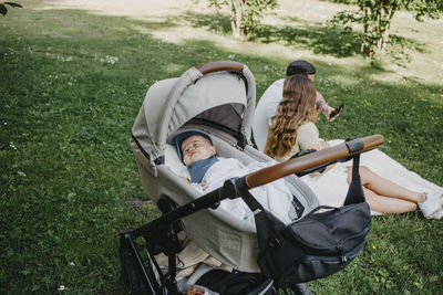 Baby boy sleeping in pram, parents in background