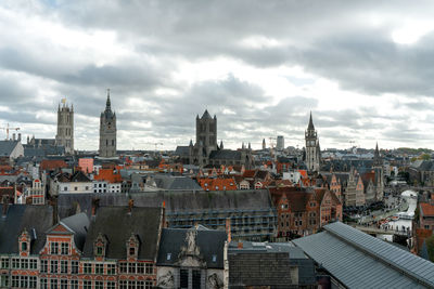 High angle view of city buildings against cloudy sky