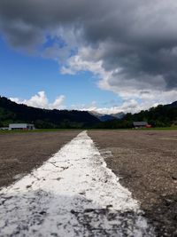 Surface level of road amidst field against sky