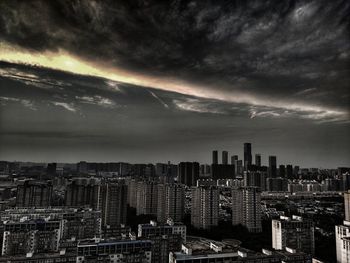 Aerial view of buildings in city against storm clouds