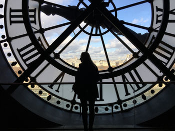 Low angle view of silhouette woman standing against clock tower