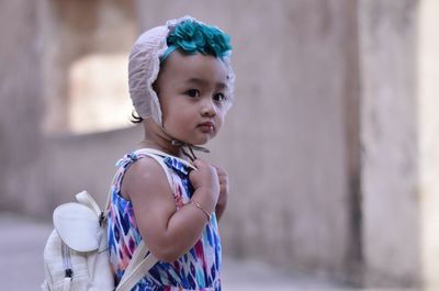 Side view of cute baby girl carrying bag