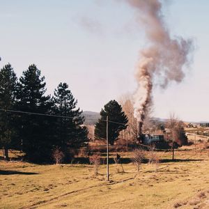 Smoke emitting from chimney on field against sky