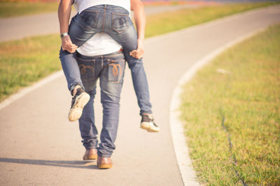 Low section of man carrying friend on back
