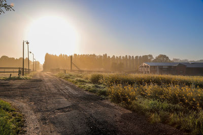 Road amidst field against clear sky