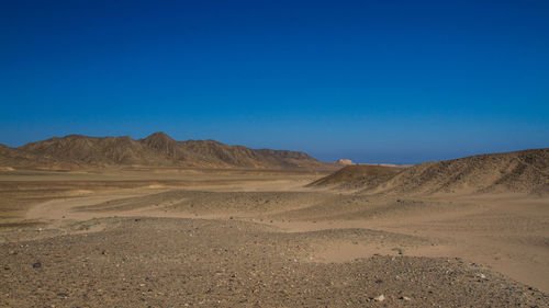 Scenic view of landscape and mountains against clear blue sky