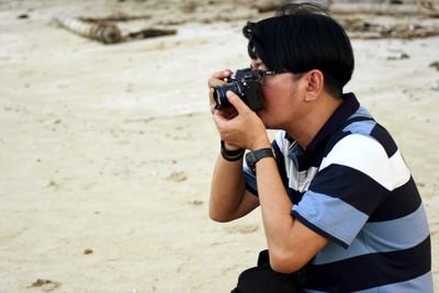 Side view of young man photographing at beach