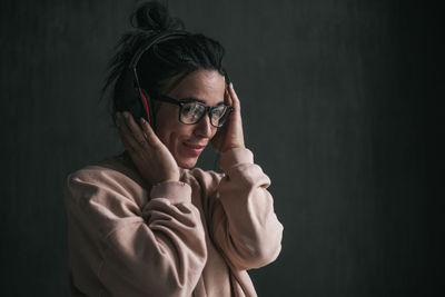 Portrait of young woman standing against black background