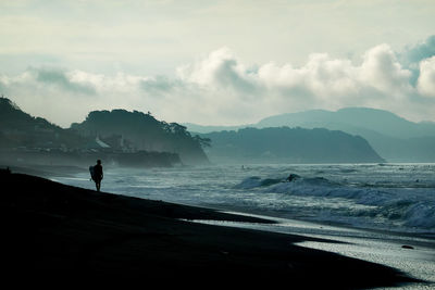 Silhouette person standing on beach against sky