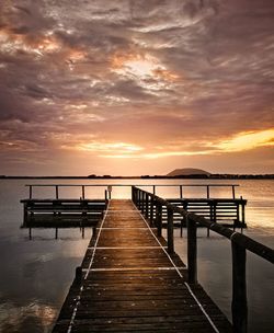 Pier over sea against sky during sunset