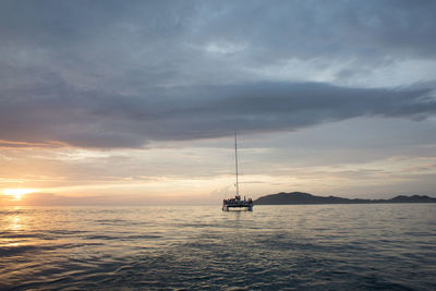 Sailboat sailing in sea against cloudy sky